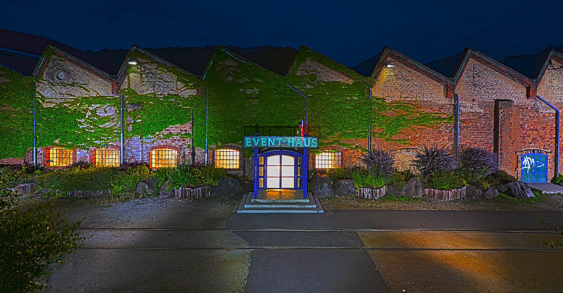 Beleuchteter Eingangsbereich des Event-Haus Alte Schmelz bei Nacht.